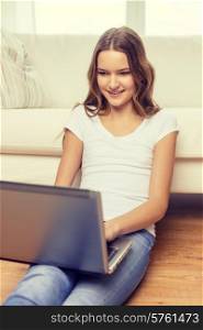 home, technology and internet concept - smiling teenage girl sitting on the floor with laptop computer at home