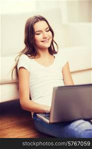 home, technology and internet concept - smiling teenage girl sitting on the floor with laptop computer at home