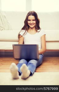 home, technology and internet concept - smiling teenage girl sitting on the floor with laptop computer at home