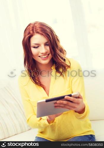 home, technology and internet concept - smiling teenage girl sitting on the couch with tablet pc computer at home