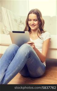 home, technology and internet concept - smiling teenage girl sitting ong the floor with tablet pc computer at home