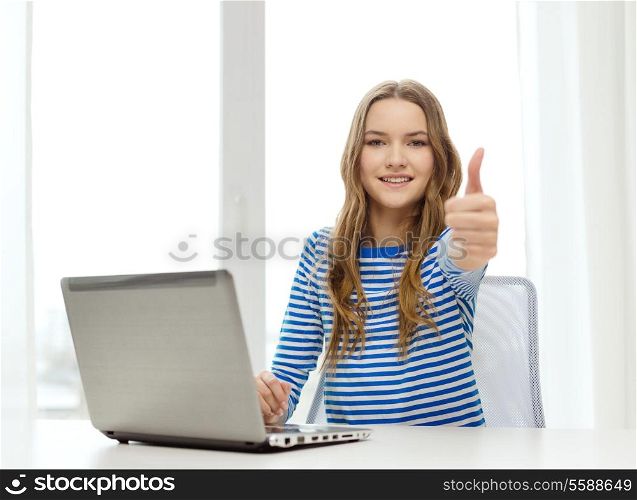 home, technology and internet concept - smiling teenage girl with laptop computer at home showing thumbs up