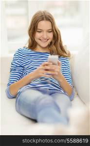 home, technology and internet concept - smiling teenage girl with smartphone lying on couch at home