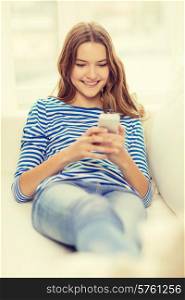 home, technology and internet concept - smiling teenage girl with smartphone lying on couch at home