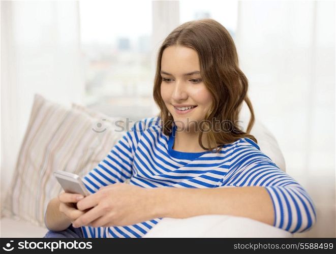 home, technology and internet concept - smiling teenage girl with smartphone sitting on couch at home