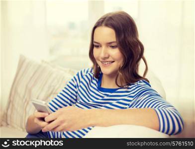 home, technology and internet concept - smiling teenage girl with smartphone sitting on couch at home