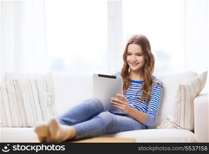 home, technology and internet concept - smiling teenge girl lying on the couch with tablet pc computer at home