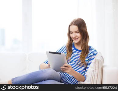 home, technology and internet concept - smiling teenge girl lying on the couch with tablet pc computer at home