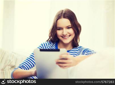 home, technology and internet concept - smiling teenge girl lying on the couch with tablet pc computer at home