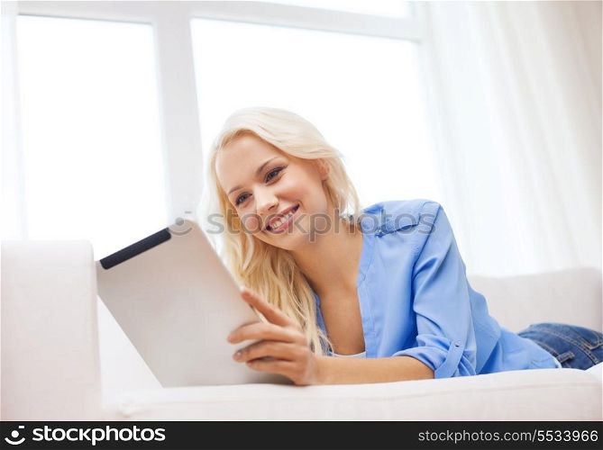 home, technology and internet concept - smiling woman lying on couch with tablet pc computer at home