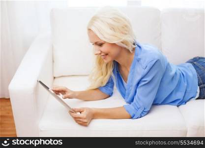 home, technology and internet concept - smiling woman lying on couch with tablet pc computer at home