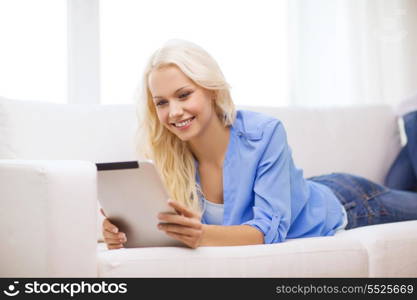 home, technology and internet concept - smiling woman lying on the couch with tablet pc computer at home