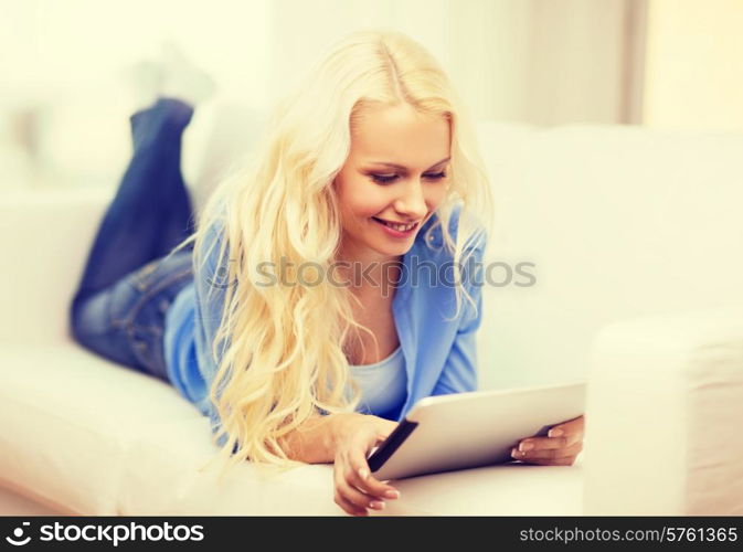 home, technology and internet concept - smiling woman lying on the couch with tablet pc computer at home