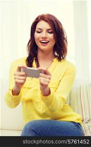 home, technology and internet concept - smiling woman playing with smartphone sitting on couch at home