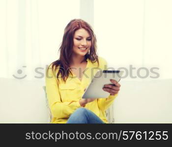 home, technology and internet concept - smiling woman sitting on couch with tablet pc computer at home