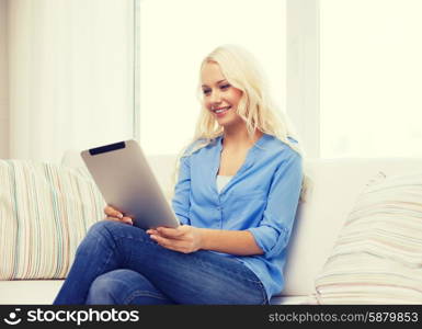 home, technology and internet concept - smiling woman sitting on couch with tablet pc computer at home
