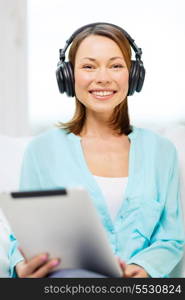 home, technology and internet concept - smiling woman sitting on the couch with tablet pc conputer and headphones at home