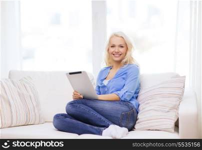 home, technology and internet concept - smiling woman sitting on the couch with tablet pc computer at home