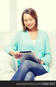 home, technology and internet concept - smiling woman sitting on the couch with tablet pc at home