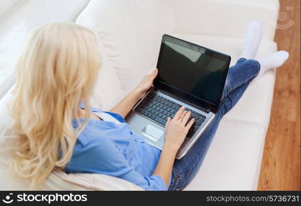 home, technology and internet concept - smiling woman with laptop computer sitting on couch at home