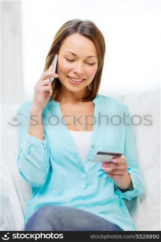 home, technology and internet concept - smiling woman with smartphone sitting on couch at home