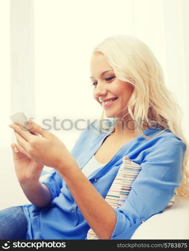 home, technology and internet concept - smiling woman with smartphone sitting on couch at home