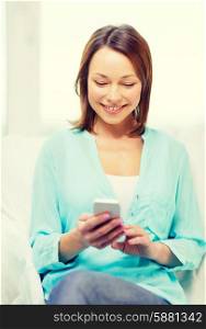 home, technology and internet concept - smiling woman with smartphone sitting on couch at home