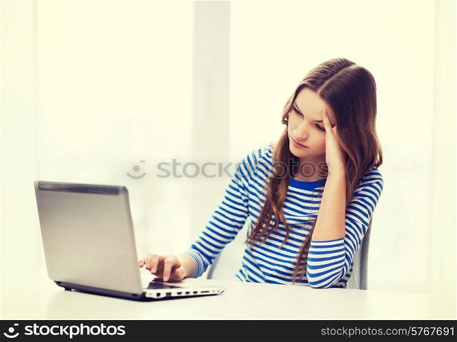 home, technology and internet concept - upset teenage girl with laptop computer at home