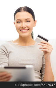 home, technology and internet concept - woman sitting on the couch with tablet pc computer and credit card at home