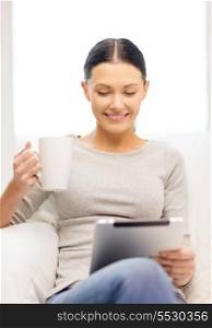 home, technology and internet concept - woman sitting on the couch with tablet pc and cup at home