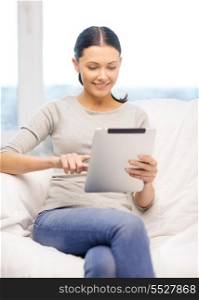 home, technology and internet concept - woman sitting on the couch with tablet pc at home