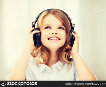 home, technology and music concept - little girl with headphones at home