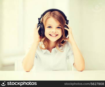 home, technology and music concept - little girl with headphones at home