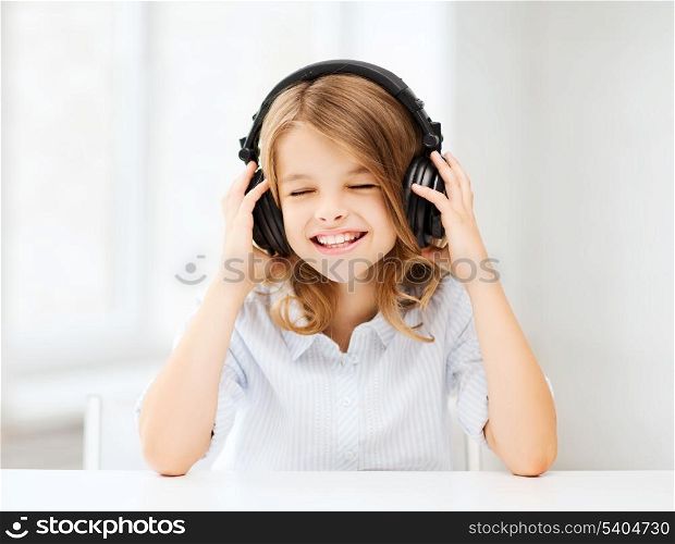 home, technology and music concept - little girl with headphones listening to music and singing