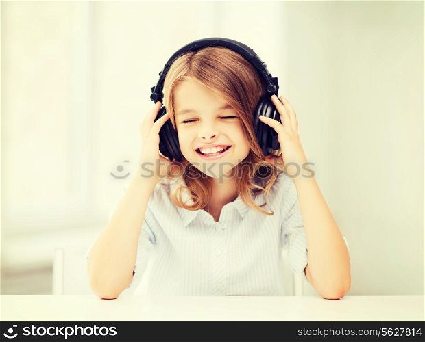 home, technology and music concept - little girl with headphones listening to music and singing