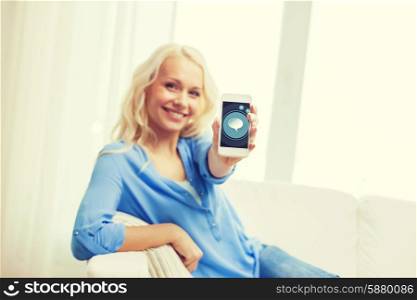 home, technology and people concept - smiling woman with showing smartphone screen sitting on couch at home