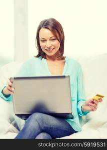 home, technology, online shopping and internet concept - smiling woman sitting on the couch with laptop computer at home