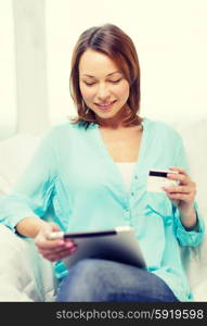 home, technology, online shopping and internet concept - smiling woman sitting on the couch with tablet pc at home