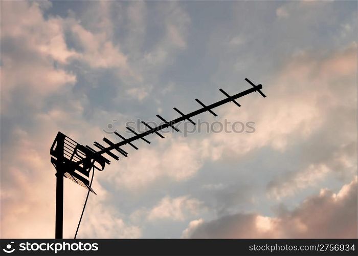 Home television antenna on the background of white and reddish evening clouds