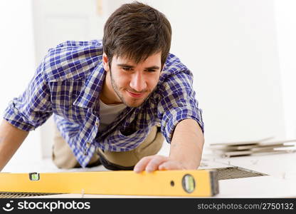 Home tile improvement - handyman with level laying down tile floor