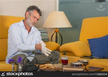 homebound man putting on medical gloves to drink a cup of tea. concept of prevention concept covid-19. man putting on medical gloves to drink a cup of tea