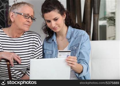 homecare helping senior woman in making online shopping