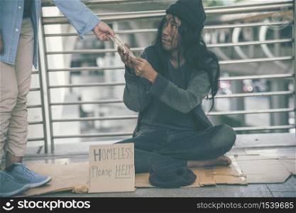 Homeless beggar man begging for money, food and help on street. Poverty despair poor man hungry and loneliness need help from man kind. woman give money to homeless on street;
