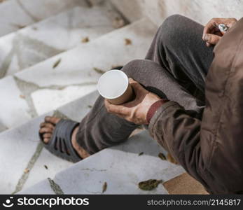 homeless man holding empty cup stairs
