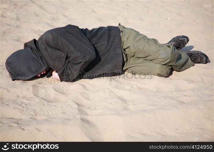 homeless man sleeping on sand, selective focus