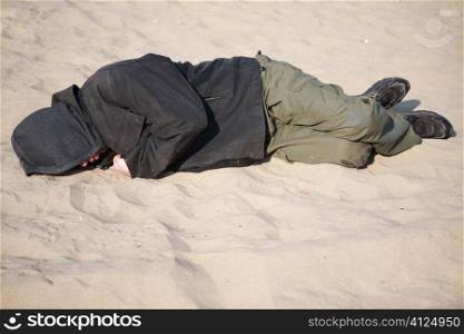 homeless man sleeping on sand, selective focus