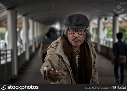 Homeless old man threaten by pointing knife to people at city sky walk. Poverty social issue and safety and danger life in town concept. Robbery and hostage in town.