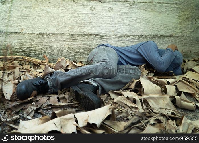 Homeless wore a gray hat and gray long-sleeve shirt. Is sleeping because of exhaustion, with the back leaning against the Siemens wall