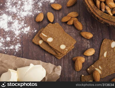 Homemade almond biscuit cookies with raw almonds and butter on wooden background