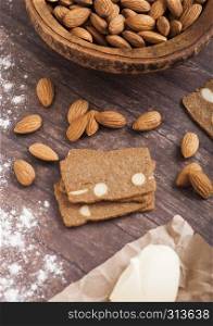 Homemade almond biscuit cookies with raw almonds and butter on wooden background